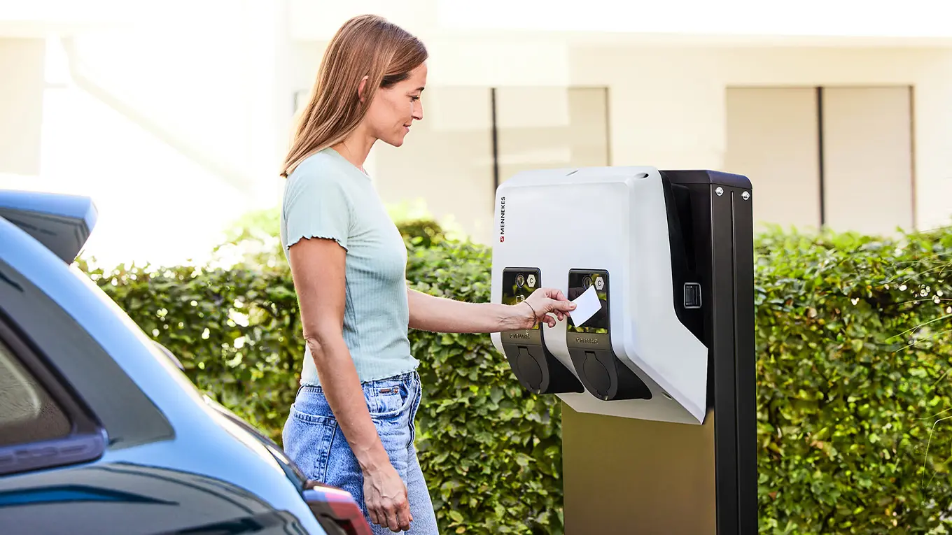 Person steht mit ihrem Auto an einer E-Ladesäule